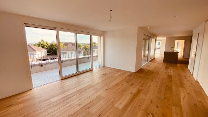 Eine moderne Küche mit einer dunkelgrauen Kücheninsel und passenden Schränken vor einer hellen Wand und Holzboden.