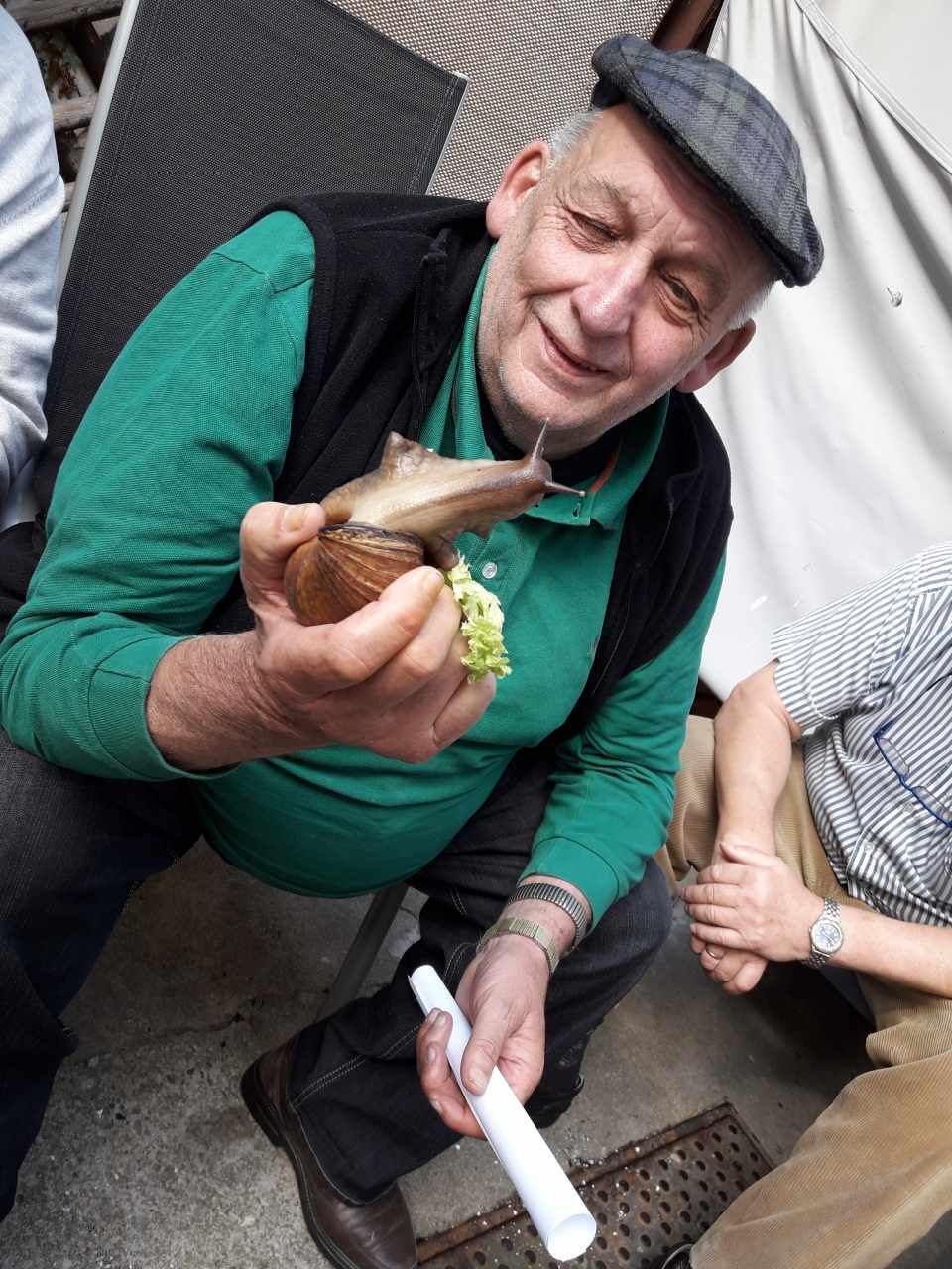 Senior hält eine große Schnecke in der Hand