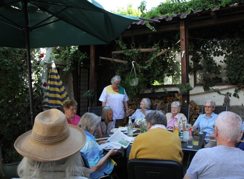 Gesellschaft sitzt gemeinsam am Tisch im Freien