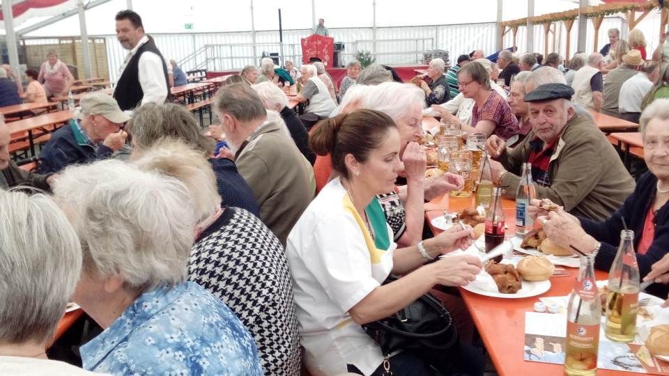 Gesellschaft sitzt gemeinsam am Tisch im Festzelt