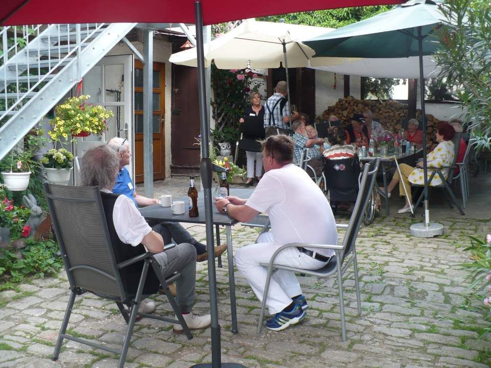 Gesellschaft sitzt gemeinsam am Tisch im Freien