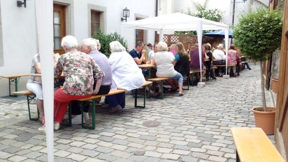 Gesellschaft sitzt gemeinsam am Tisch im Freien