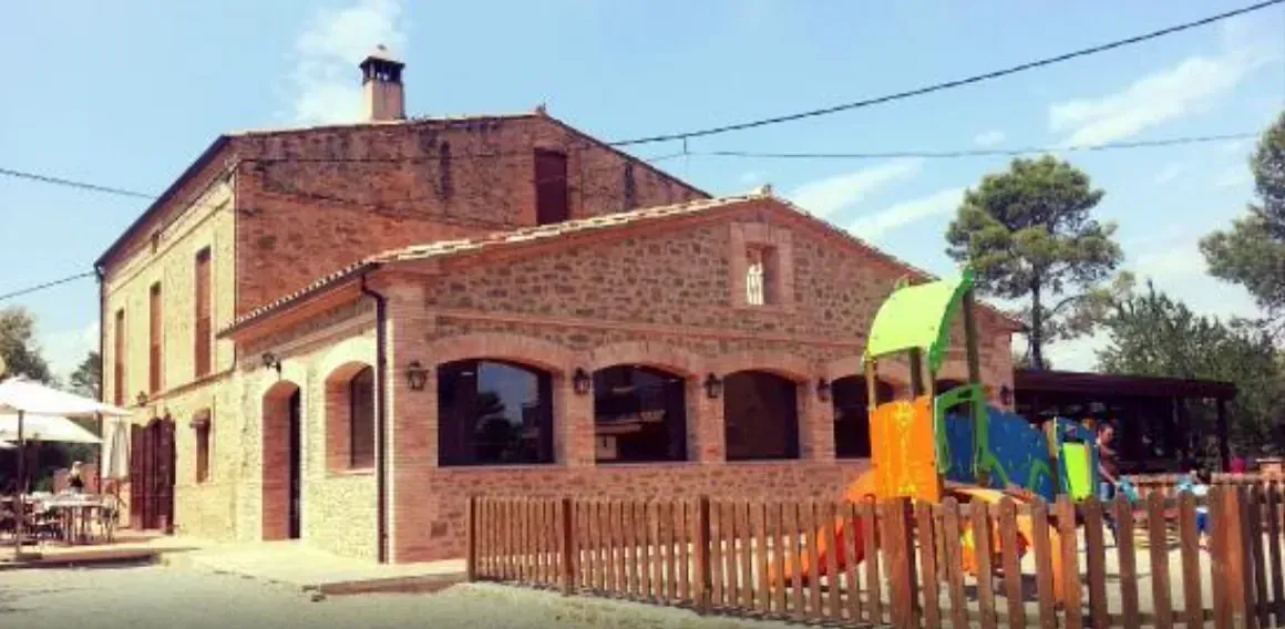 Un gran edifici de maó amb un parc infantil al davant.