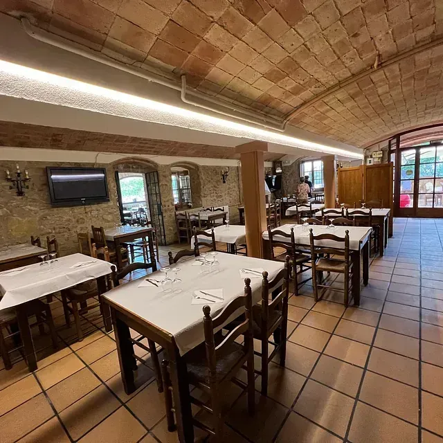 Un restaurant amb taules i cadires i un televisor a la paret.