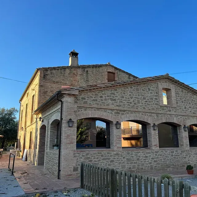 Un gran edifici de pedra amb una tanca de fusta al davant
