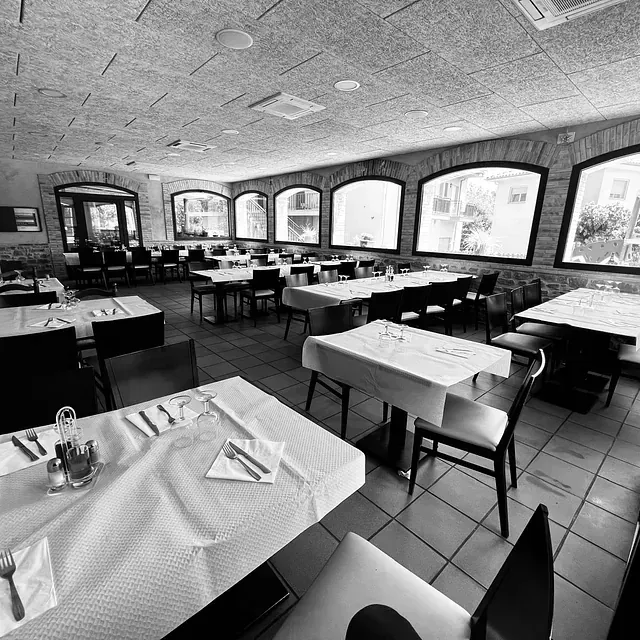 Una foto en blanc i negre d'un restaurant amb taules i cadires