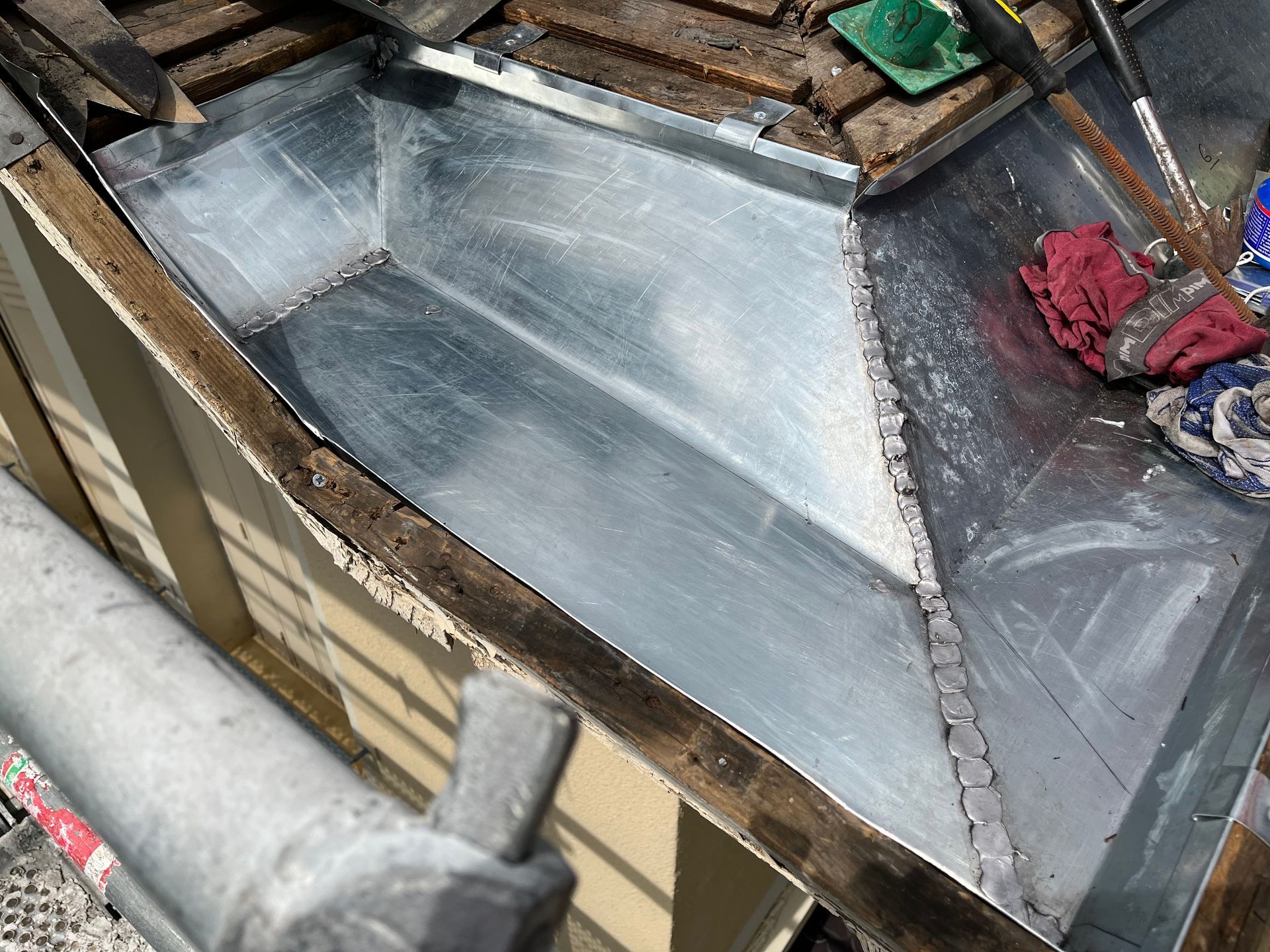 Nouvelle bande de solin métallique installée dans une noue de toit, montrant des tôles d'acier galvanisé se chevauchant et assemblées par une soudure