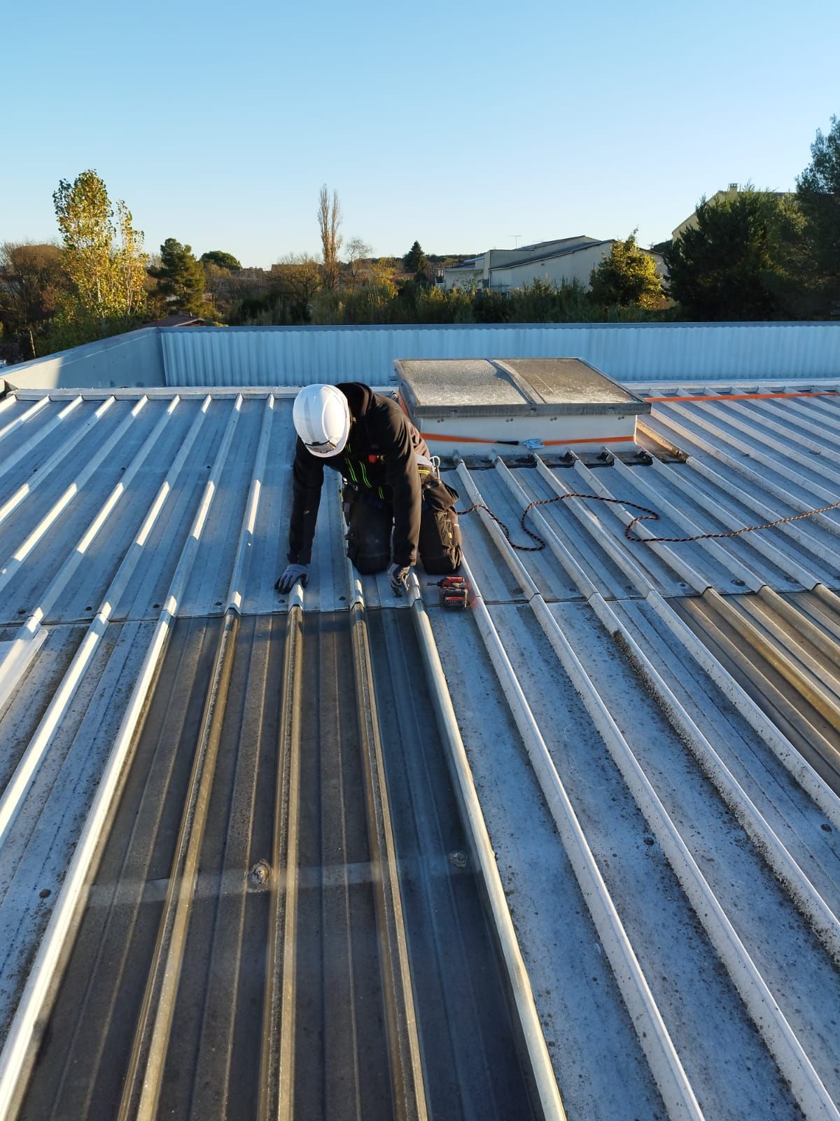 Un homme sur un toit installe des plaques en tôle