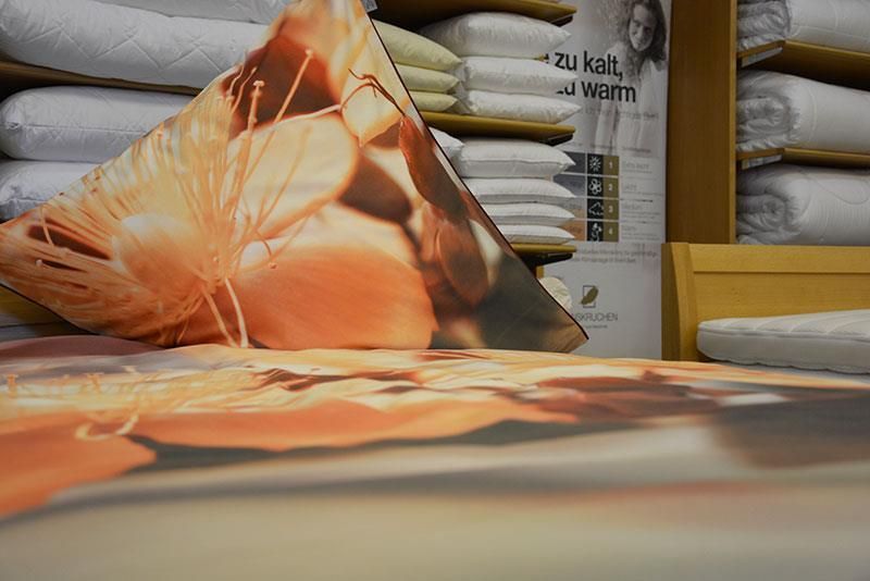 Ein Kissen mit einer Blume darauf liegt auf einem Bett