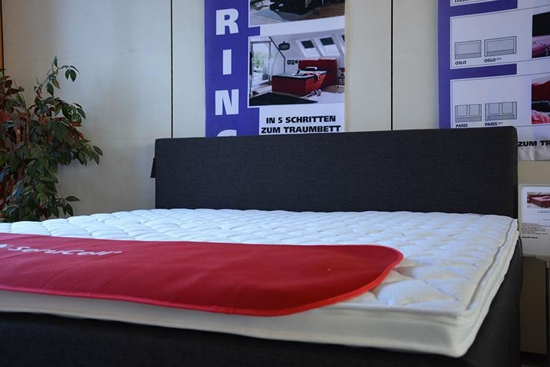 Ein Bett mit einer Matratze und einem Schild mit der Aufschrift „Rin“ darauf