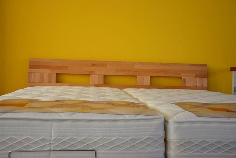 Ein Bett mit zwei Matratzen und einem hölzernen Kopfteil