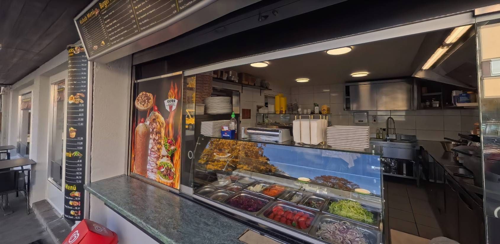 Ein Ladenlokal mit einer Auslage für Speisen und einer Speisekarte, wahrscheinlich ein Schnellrestaurant.