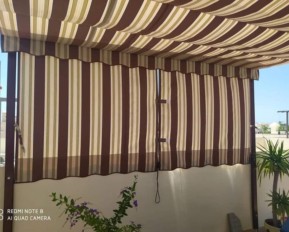 Un toldo a rayas cuelga sobre una pared blanca.