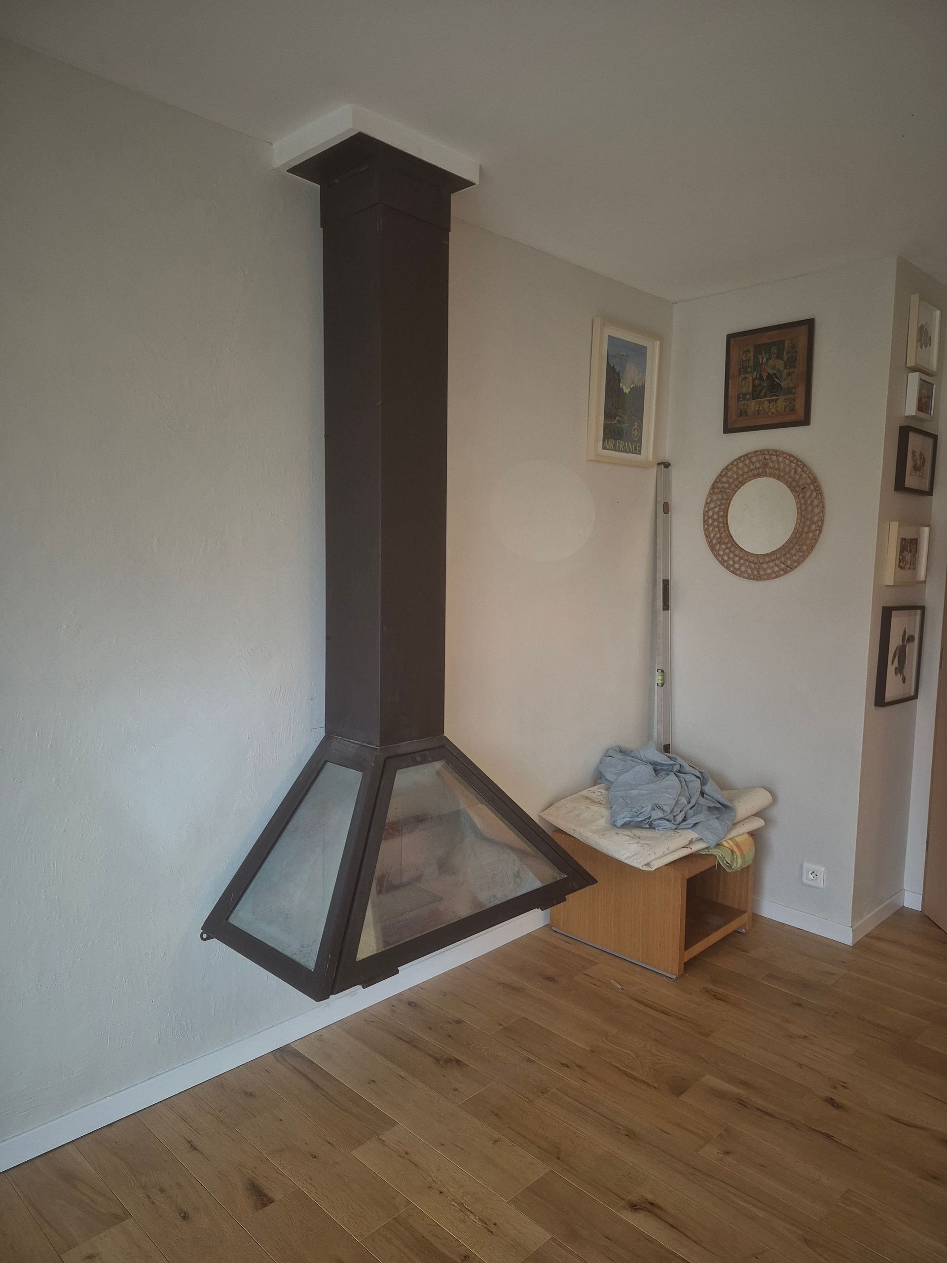 Une hotte de cuisine noire moderne au-dessus d'une cuisine avec parquet et murs blancs.