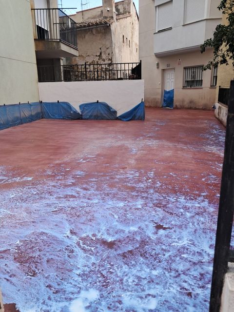 Patio rojo vacío con paredes azules y blancas y algunas puertas azules cerradas.