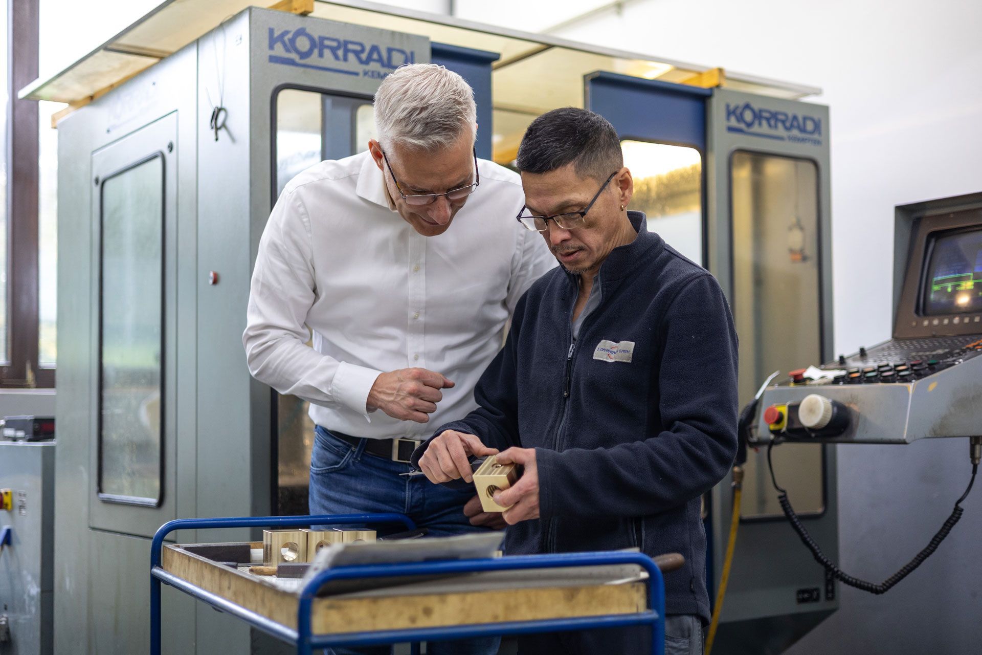 Zwei Männer stehen nebeneinander und schauen auf eine Maschine .