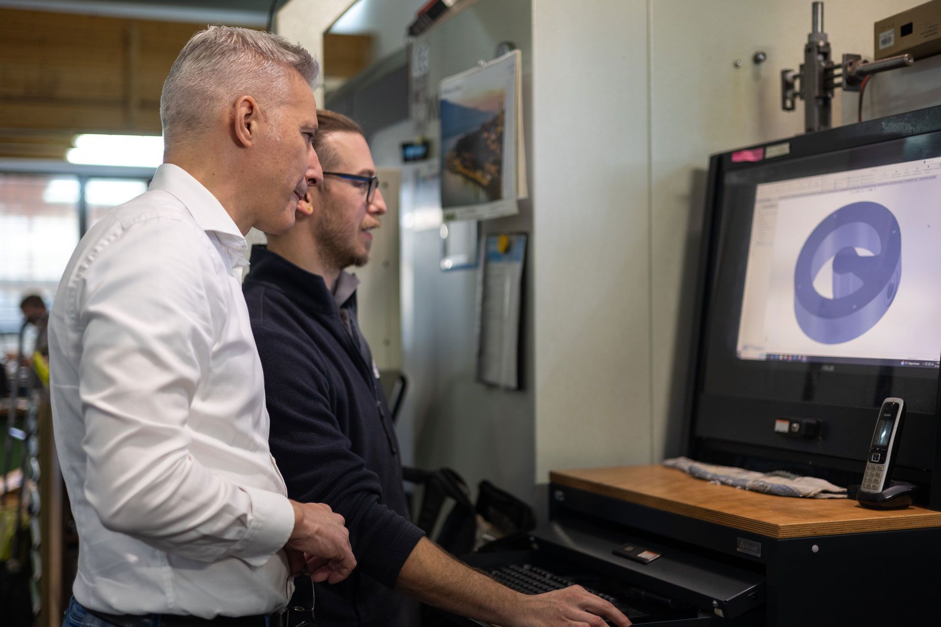 Zwei Männer stehen nebeneinander und schauen auf einen Computerbildschirm .