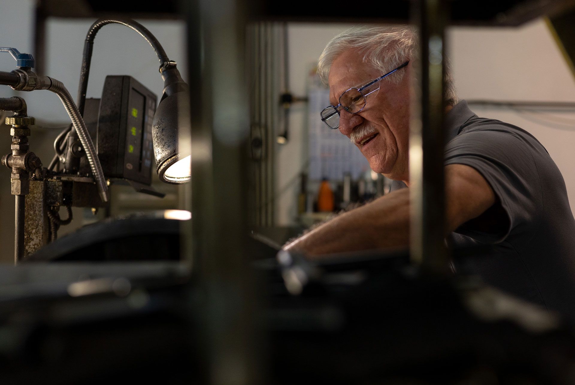Ein Mann mit Brille arbeitet an einer Maschine in einer Fabrik .