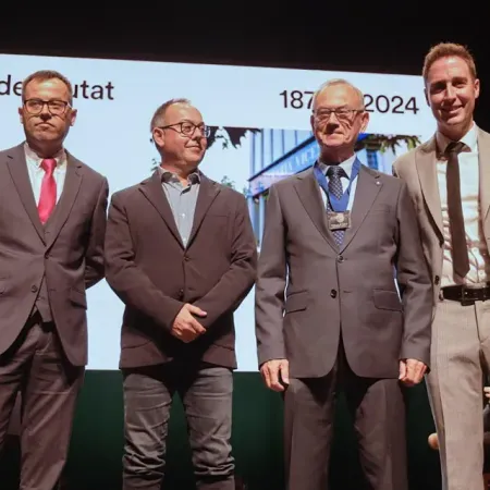 Un grupo de hombres con traje y corbata están parados frente a una pantalla con el año 2024 en ella.