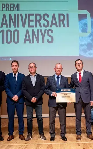 Un grupo de hombres con traje y corbata están de pie en un escenario sosteniendo un certificado.