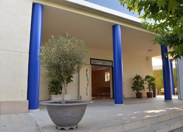 Un edificio con columnas azules y plantas en macetas en el frente.