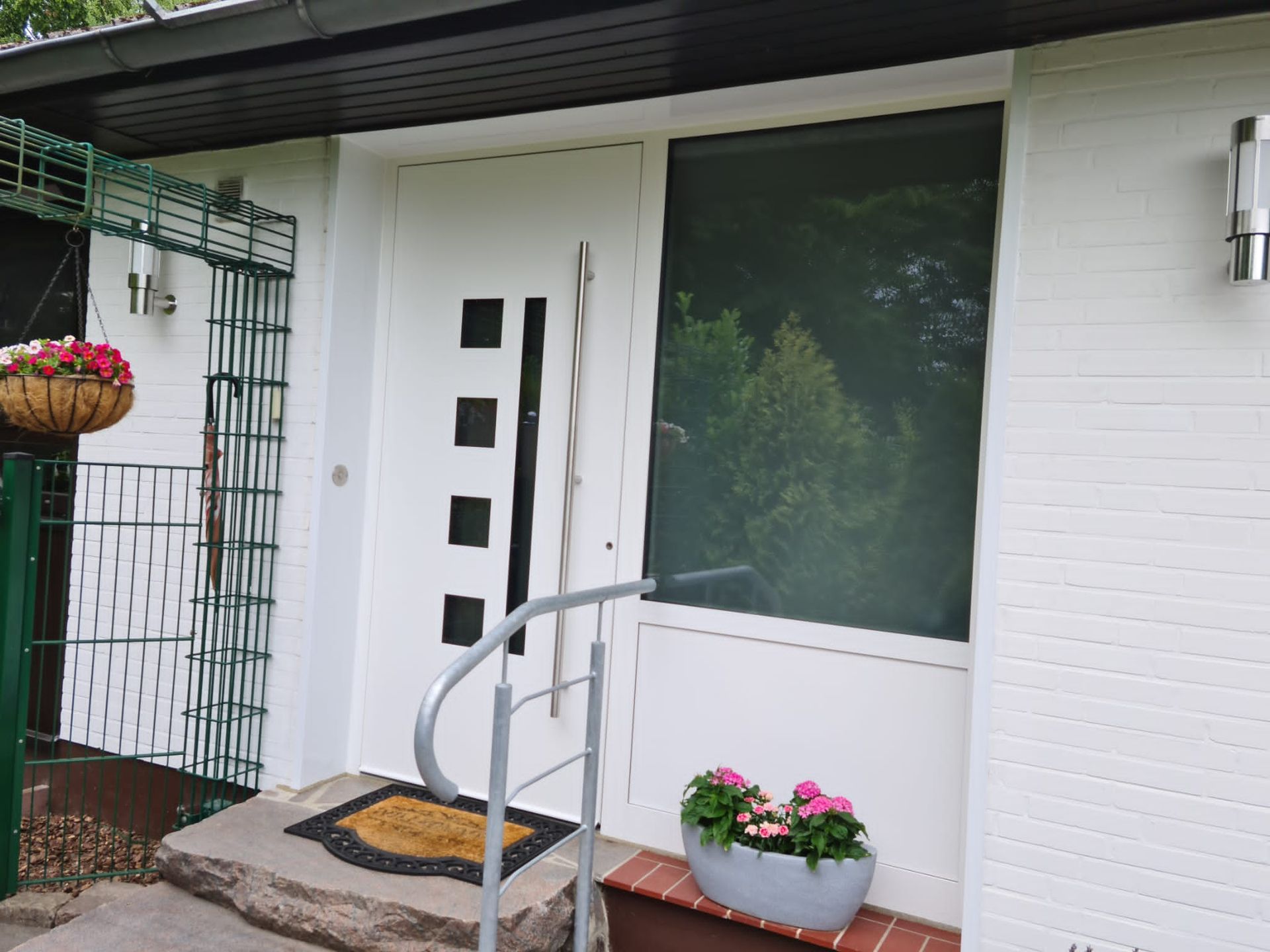 Ein weißes Haus mit einer weißen Haustür mit Glaseinsätzen.