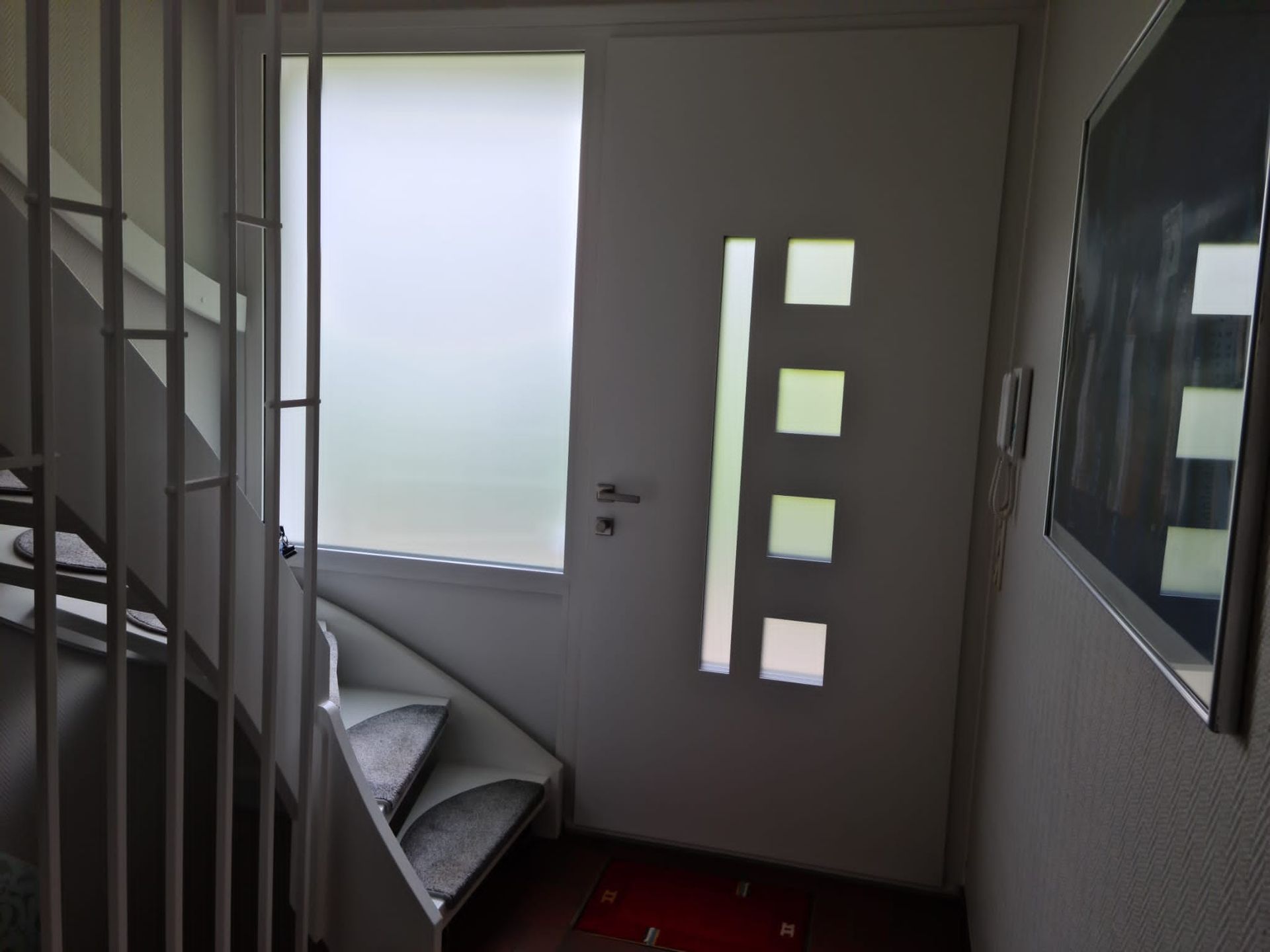 Ein Flur mit einer Wendeltreppe und einer weißen Tür mit Glaseinsätzen.