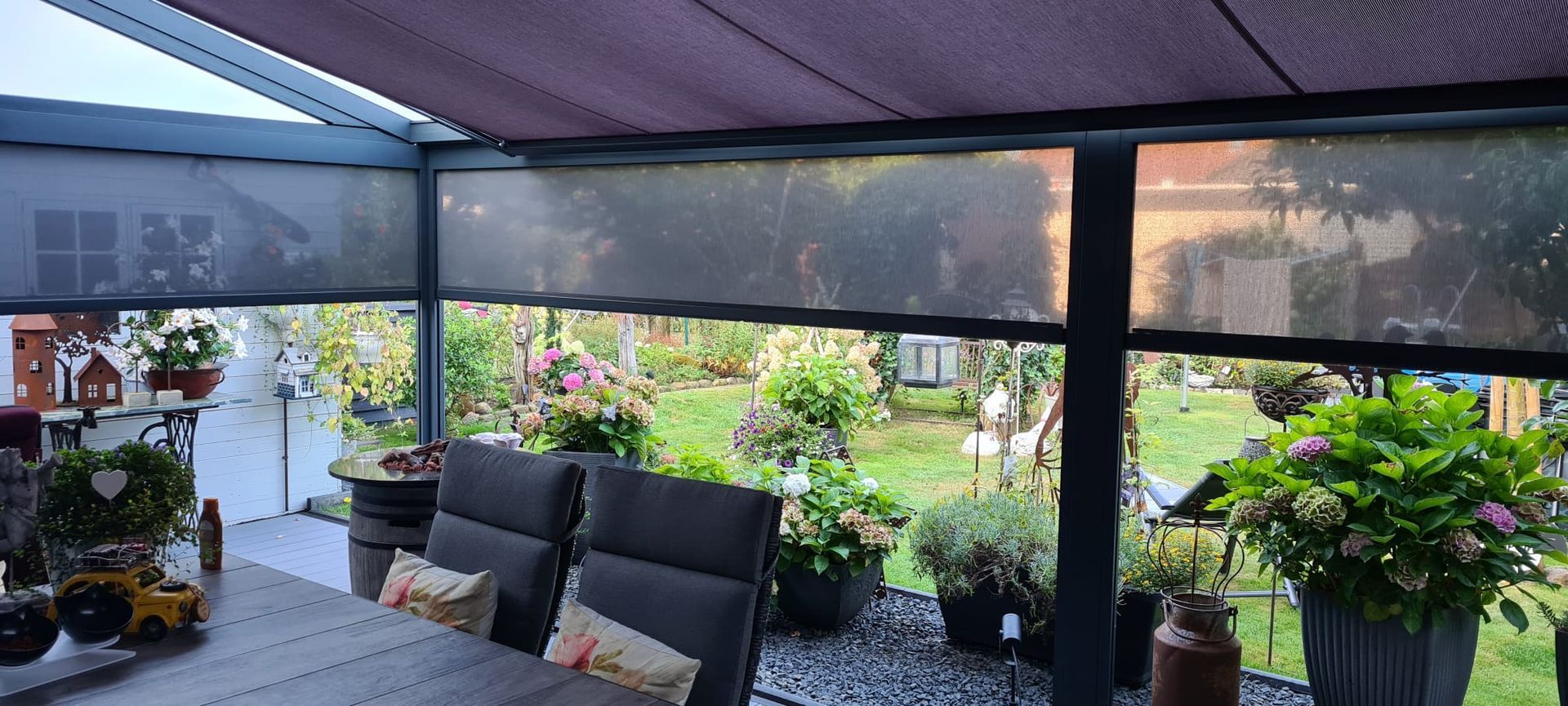 Eine Terrasse mit Tisch und Stühlen und einer Markise mit Sonnenschutz.