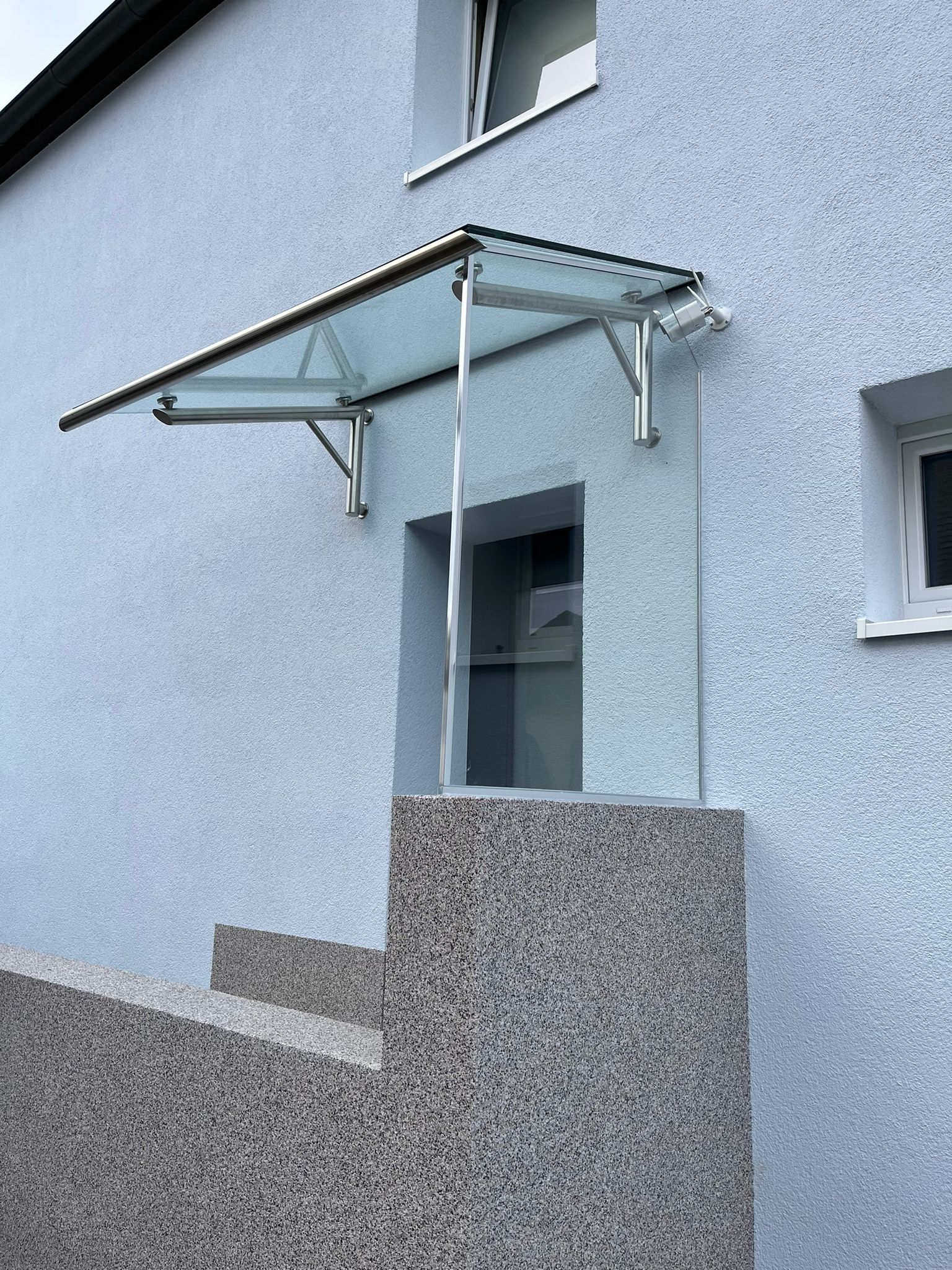 An der Seite eines Gebäudes ist ein Glasdach angebracht.