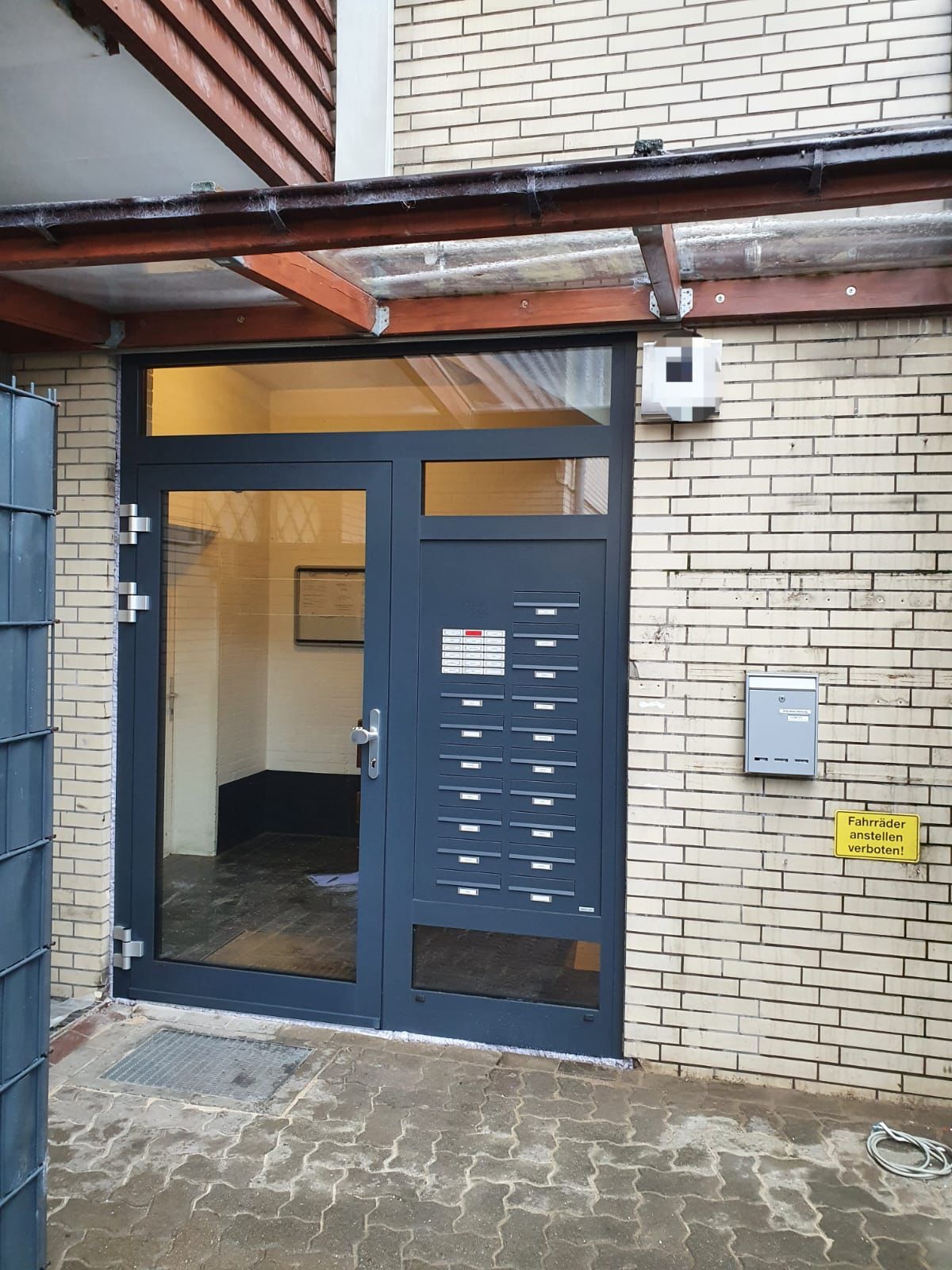 Ein Backsteingebäude mit einer schwarzen Tür und einem integrierten Briefkasten.