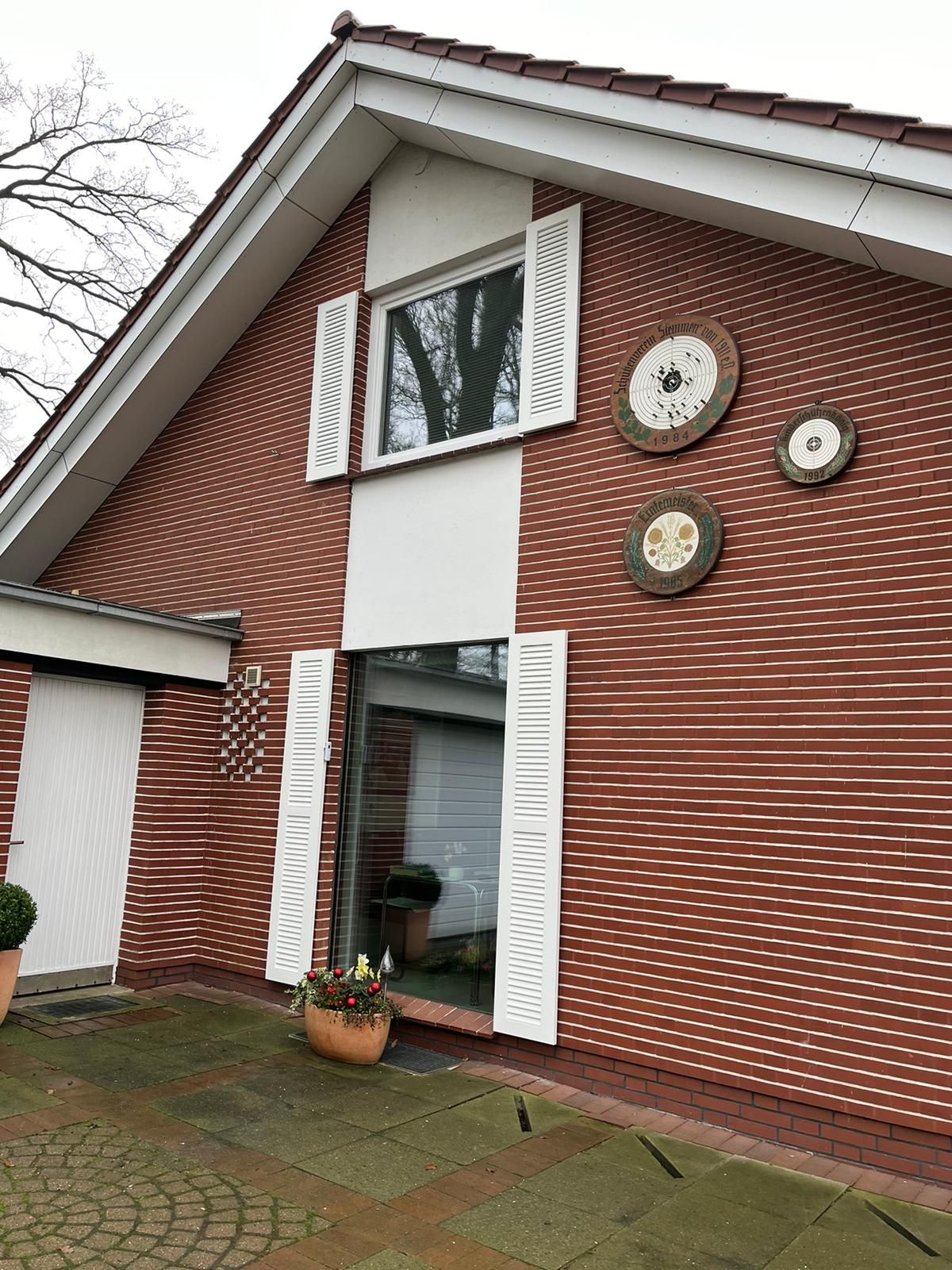 Ein rotes Backsteinhaus mit weißen Fensterläden und Uhren an der Wand.