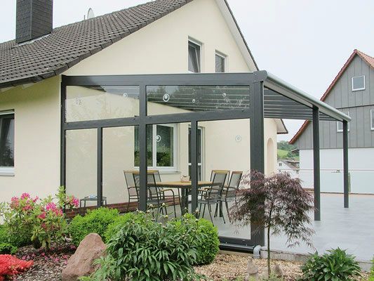 Ein Haus mit einer Terrasse mit einem Tisch und Stühlen darauf