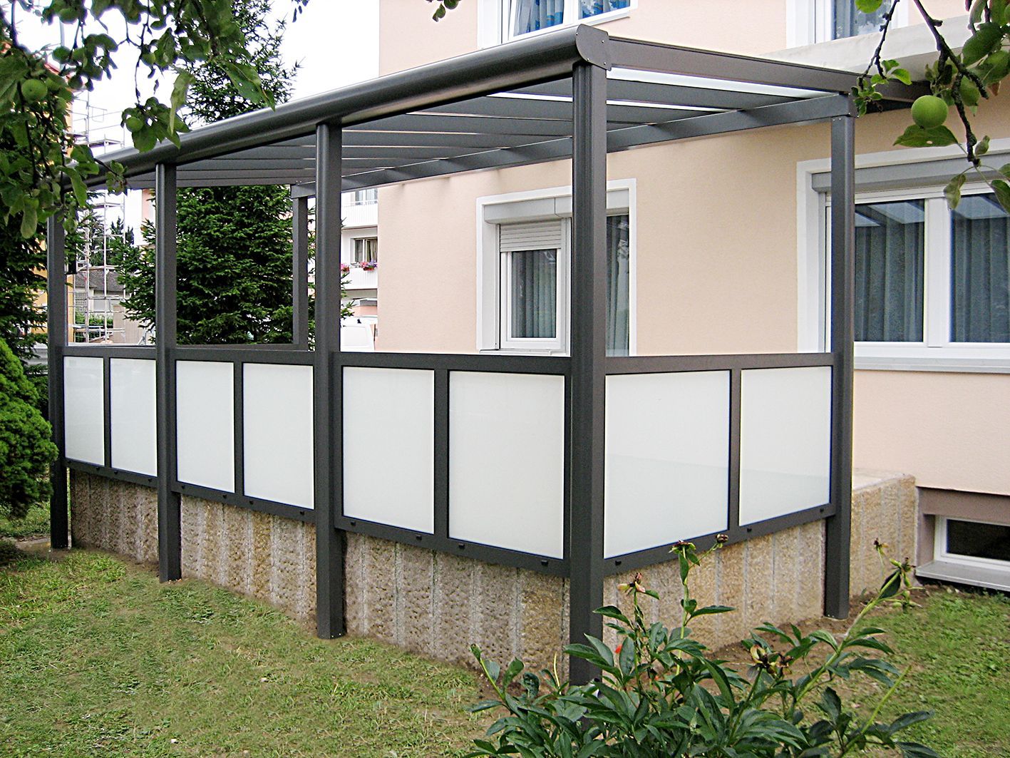 Ein Haus mit einer Pergola an der Seite