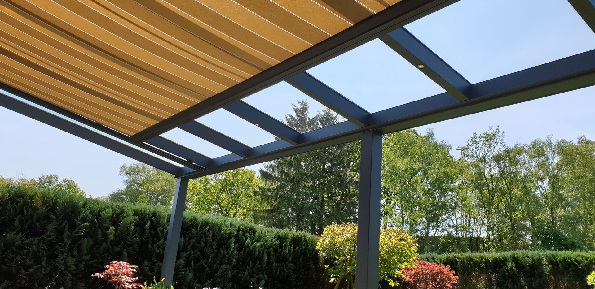 Eine Pergola mit Baldachin über einer Terrasse mit Bäumen im Hintergrund.