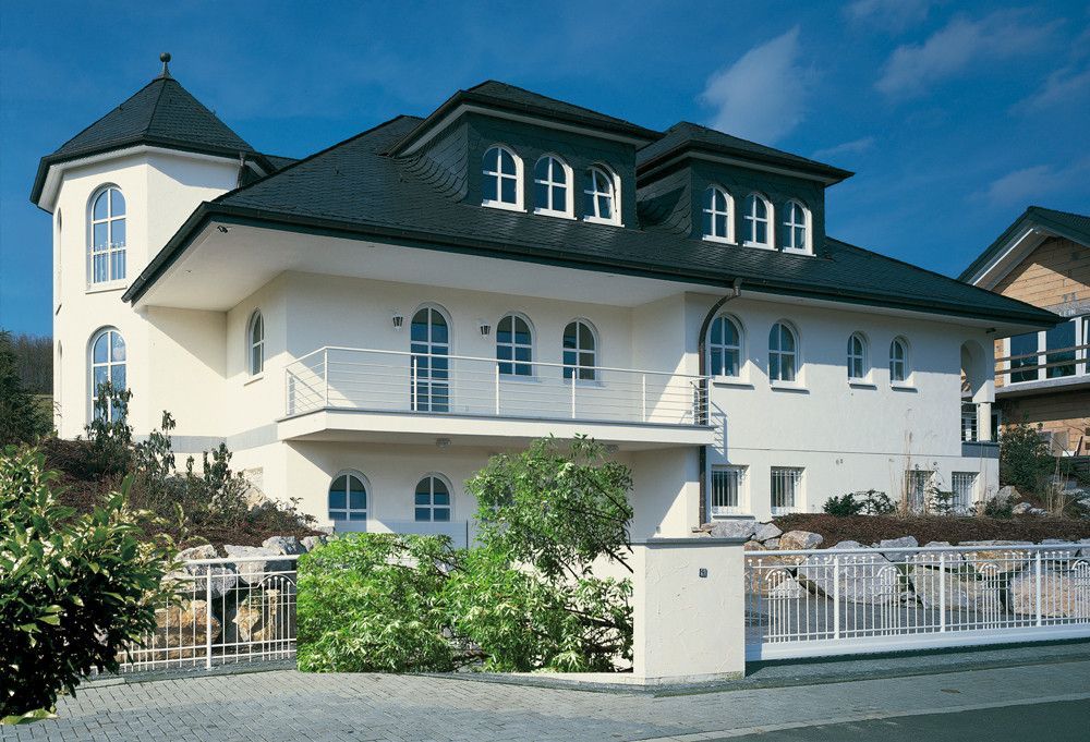 Ein großes weißes Haus mit schwarzem Dach und Balkonen