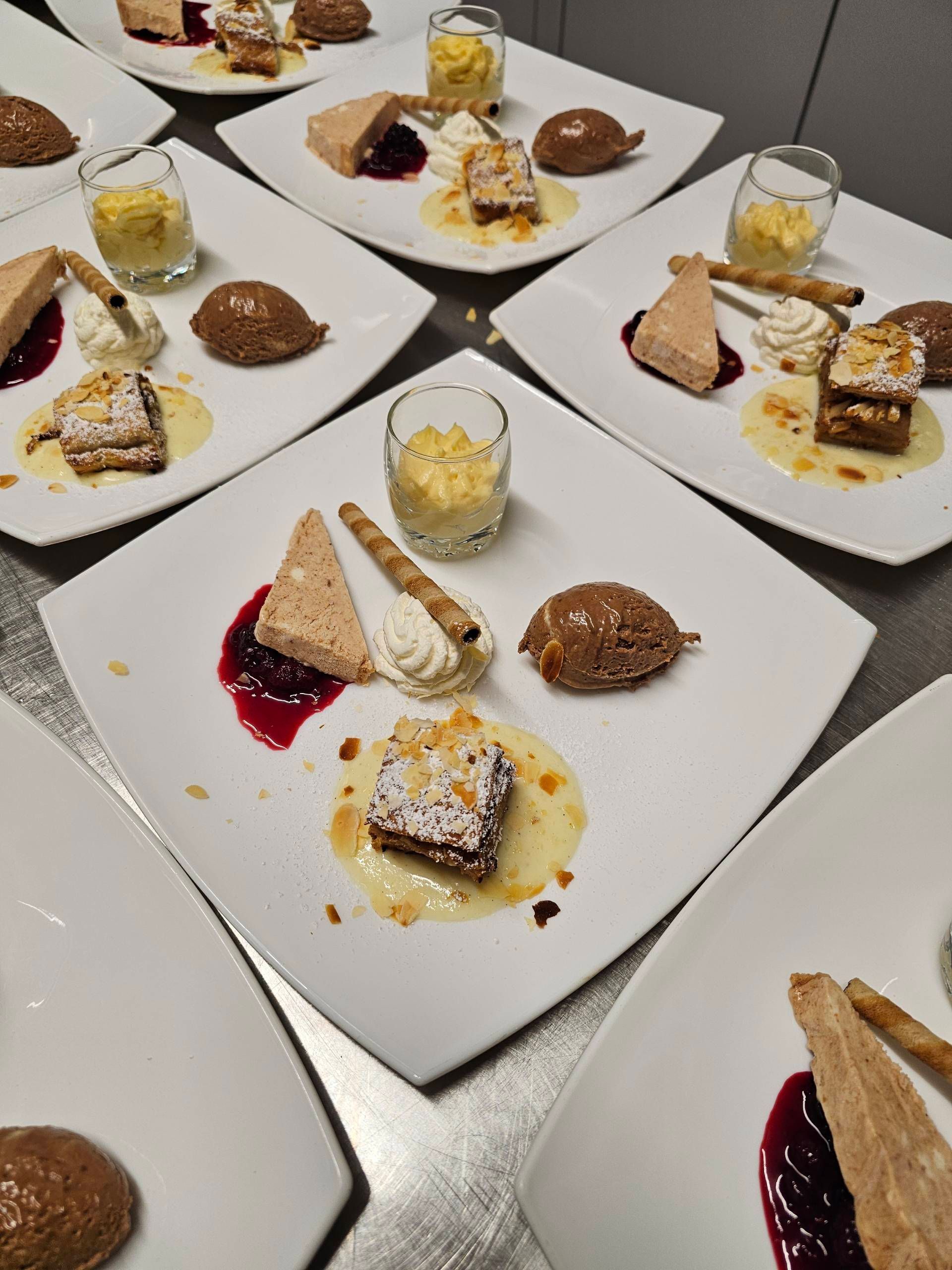 Auf einem Tisch standen Dessertteller mit verschiedenen Gebäcksorten und Sahne, jeweils dazu ein kleines Glas Mousse.