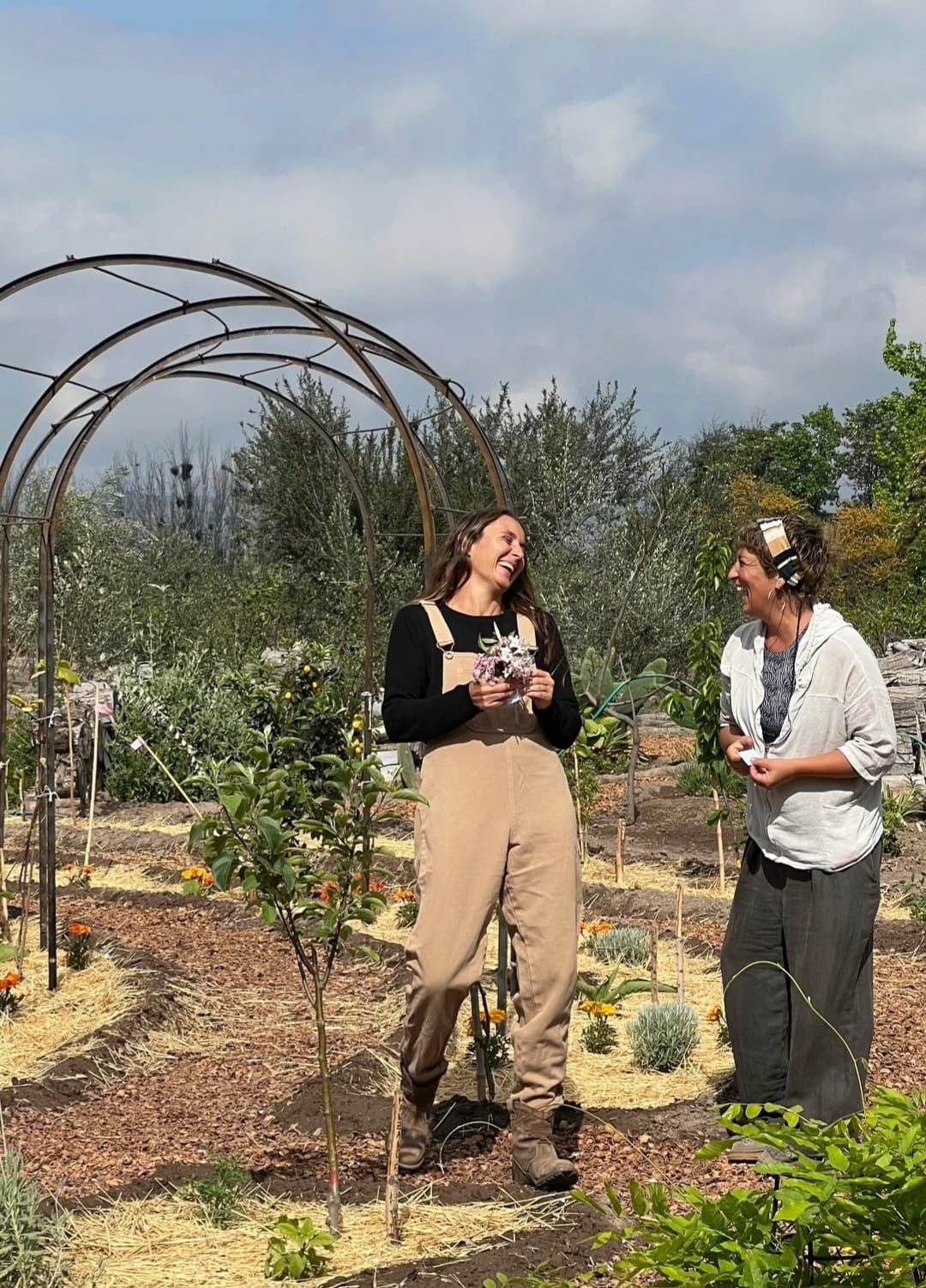 Tres mujeres posando en un bosque; una arrodillada, las demás de pie, todas sonriendo.