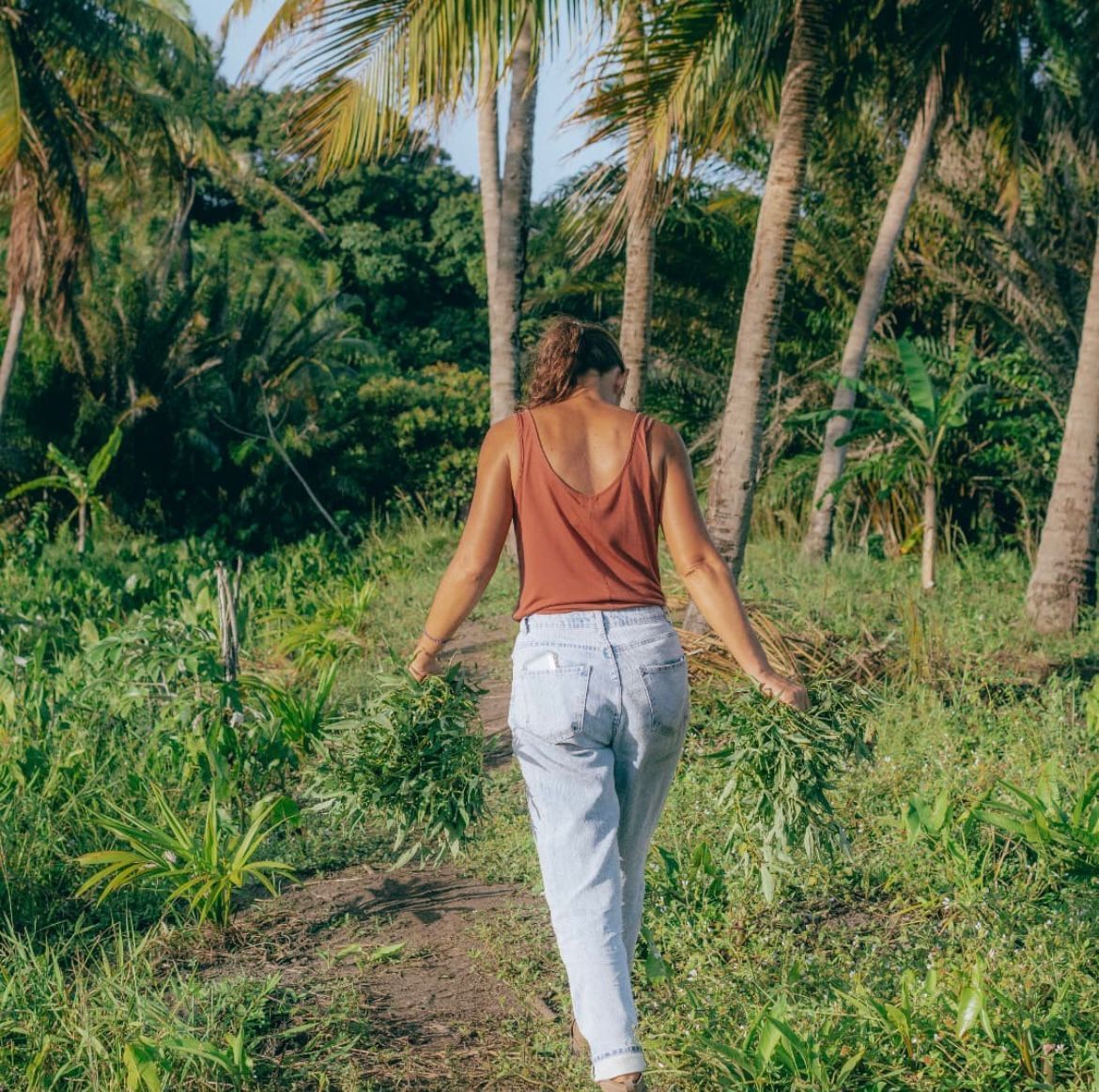 Mujer extendiendo hierba seca en un cantero de jardín, al aire libre.