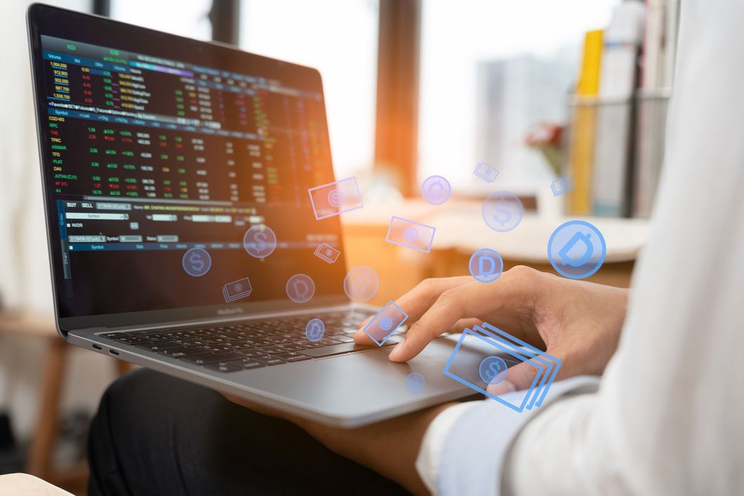 Persona que usa una computadora portátil que muestra datos del mercado de valores, con íconos digitales superpuestos.