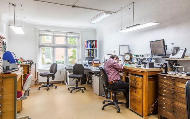 Ein Mann sitzt in einer Werkstatt an einem Schreibtisch.