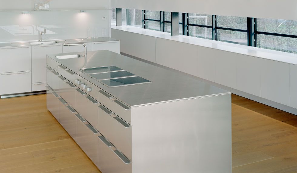 Eine Küche mit einer Arbeitsplatte aus Edelstahl und weißen Schränken
