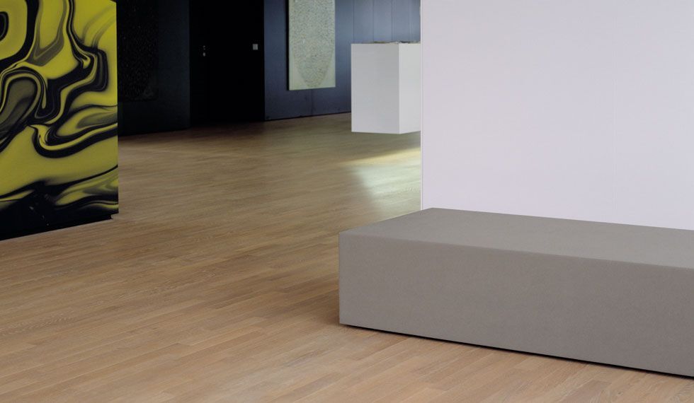 Ein Raum mit Holzboden und einer grauen Bank