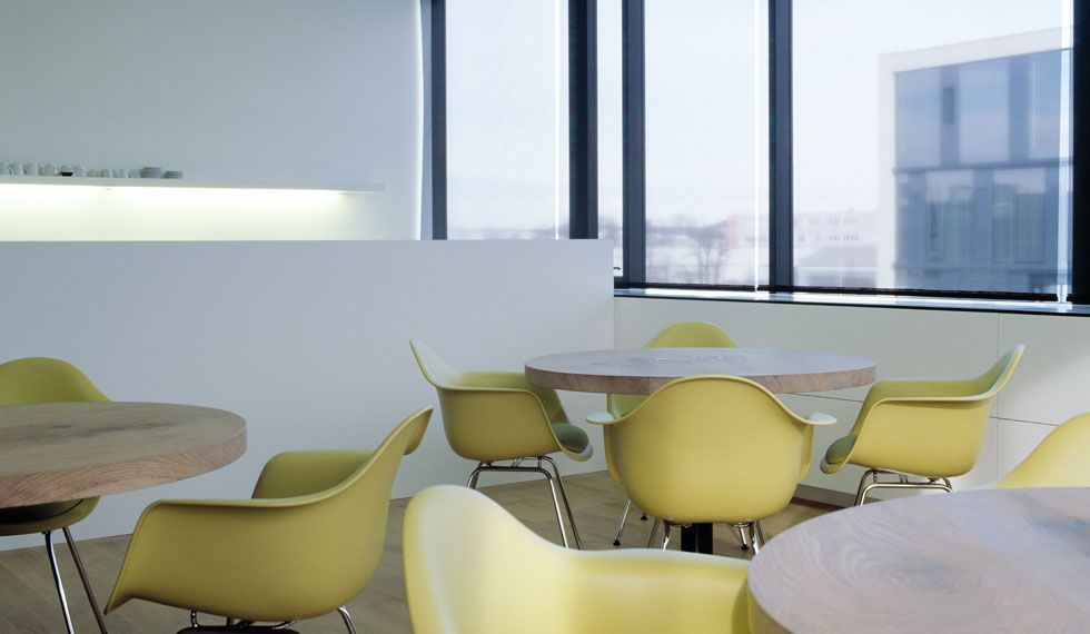 Ein Raum mit gelben Stühlen und Tischen vor einem Fenster