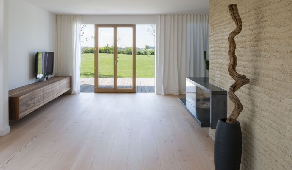 Ein Wohnzimmer mit Hartholzböden, einem Fernseher, einer Vase und einer Glasschiebetür.