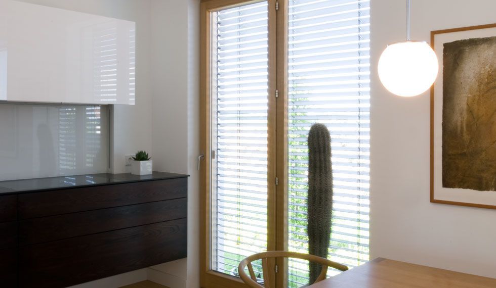 Ein Esszimmer mit Tisch und Stühlen vor einem Fenster mit Jalousien.