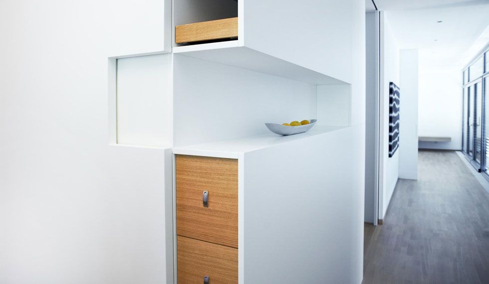 Ein weißes Regal mit Holzschubladen in einem Flur.