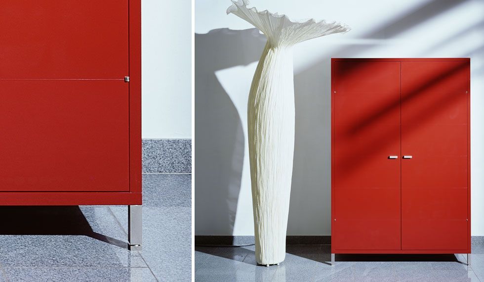 Ein roter Schrank mit einer weißen Vase davor