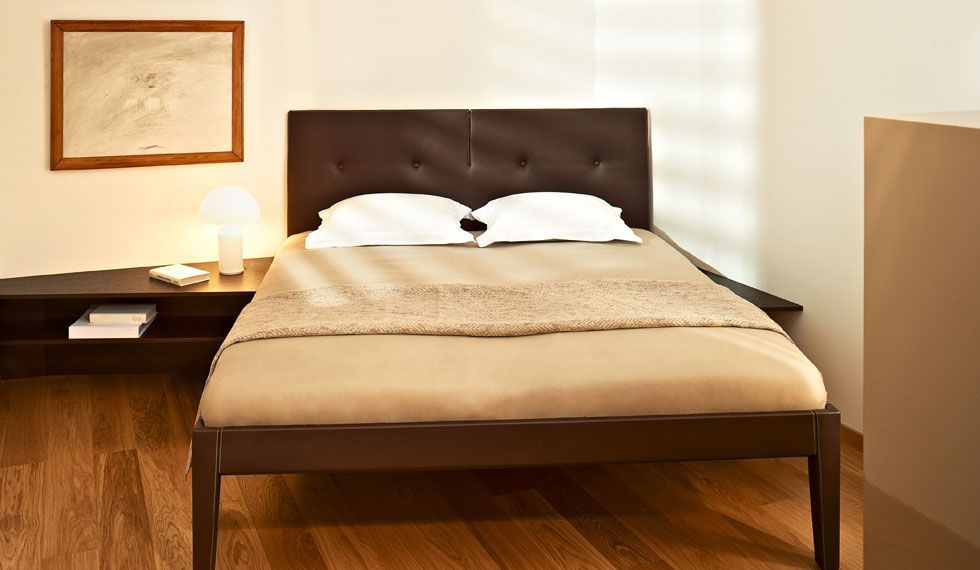 Ein Bett mit einem braunen Kopfteil steht in einem Schlafzimmer