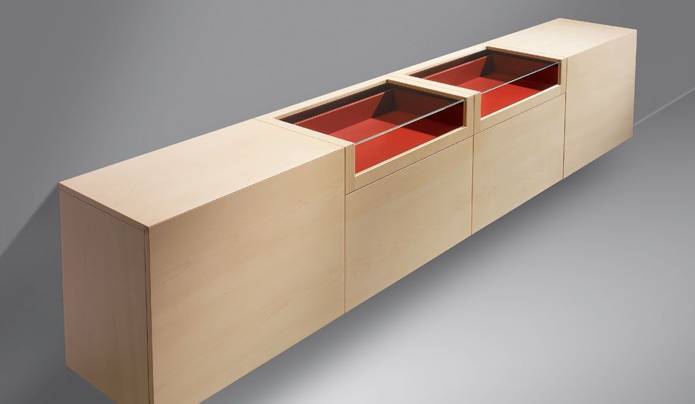 Ein langer Holzschrank mit roten Schubladen und einer Glastür.