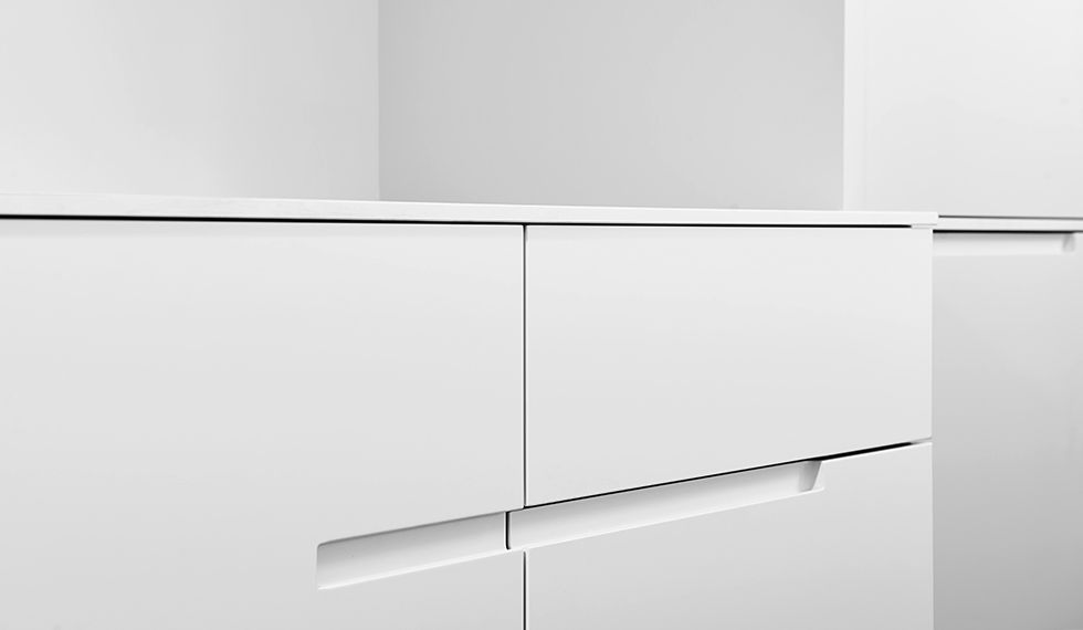 Eine Nahaufnahme eines weißen Schranks mit einem Griff aus Edelstahl.